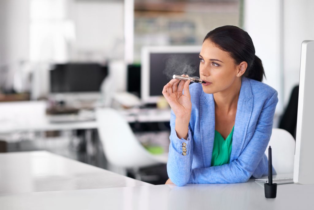 Shot of a businesswoman smoking and electronic cigarette in an office